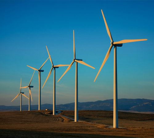 A photograph of a line of wind turbines on land.