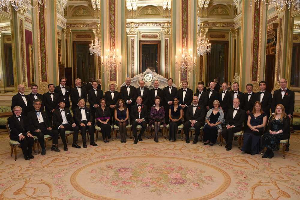 Formal group shot of 33 people, in black tie, facing camera in two rows