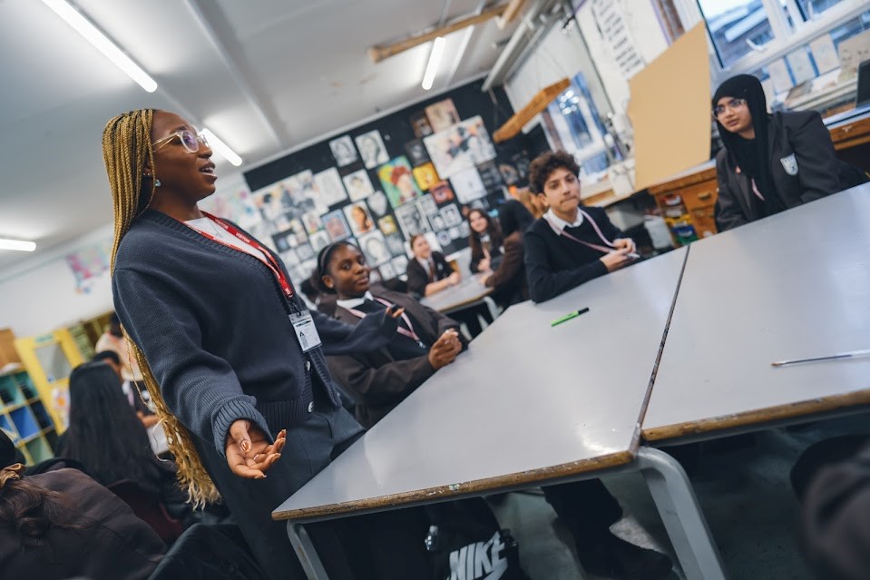 A female student standing at a table talking to other students