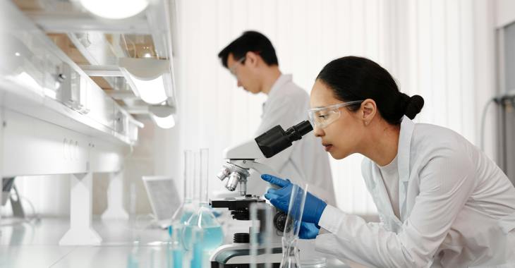 Woman Using Microscope In Laboratory