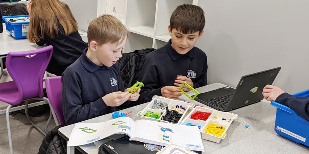 Children playing with engineering construction block toys in a classroom.