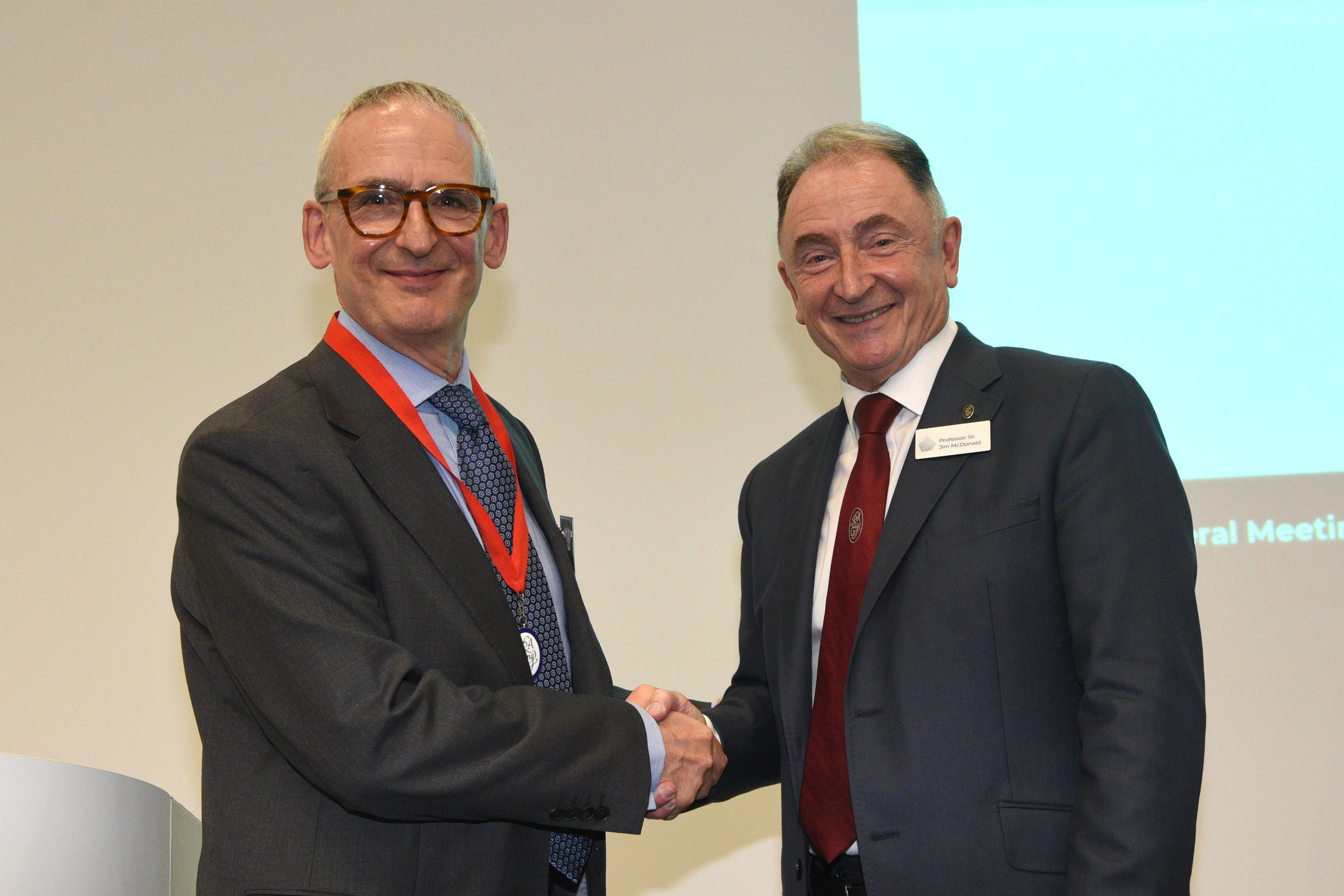 Two white men shaking hands on a stage