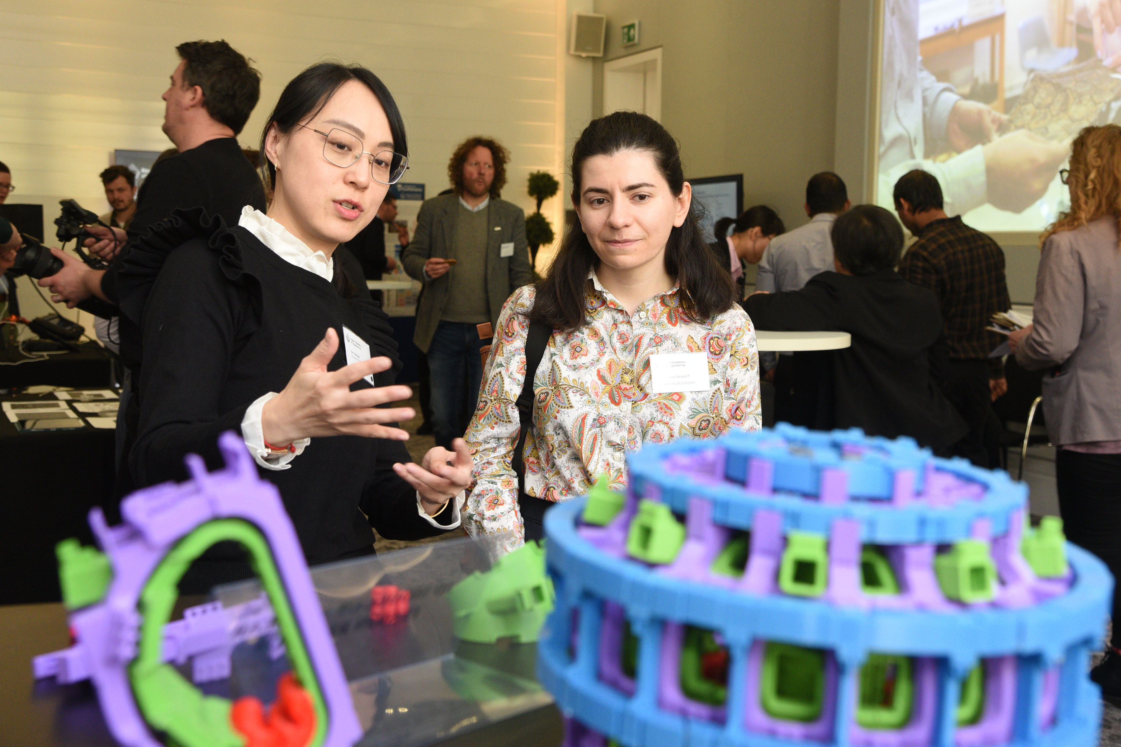 Two women standing in front of a table with colourful plastic models