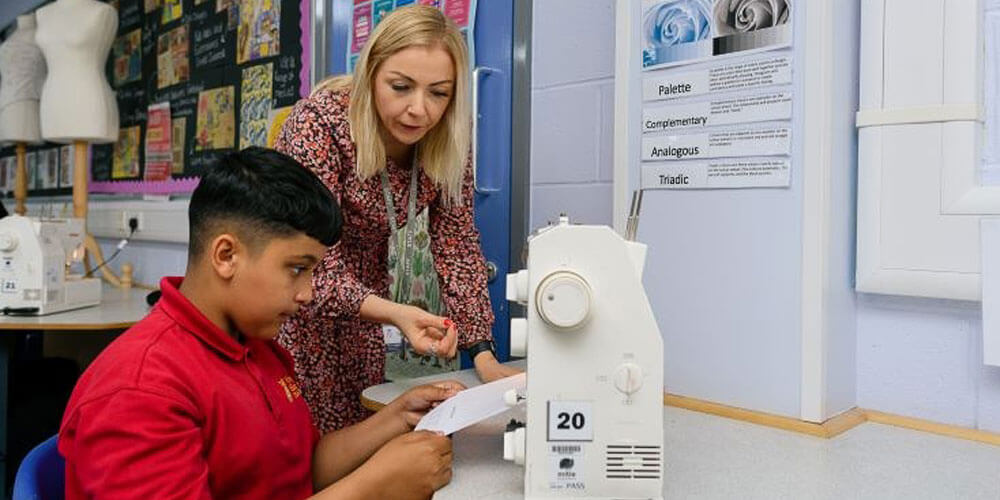 A teacher and student looking at paper in a classroom.