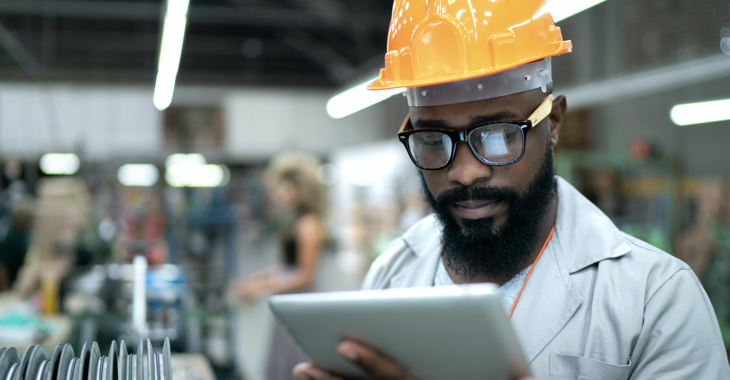 Black male engineer in helmet with tablet