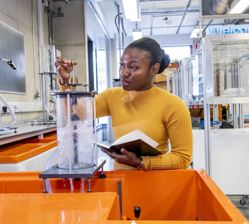 Black woman working in a lab wearing an orange jumper