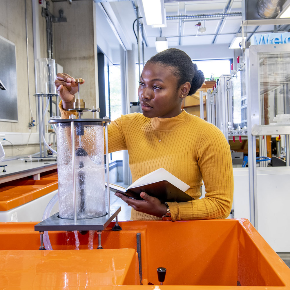 Black woman working in a lab wearing an orange jumper