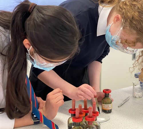 School children wearing face masks performing a science experiment.