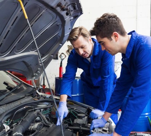 Two Technicians Working On A Car 