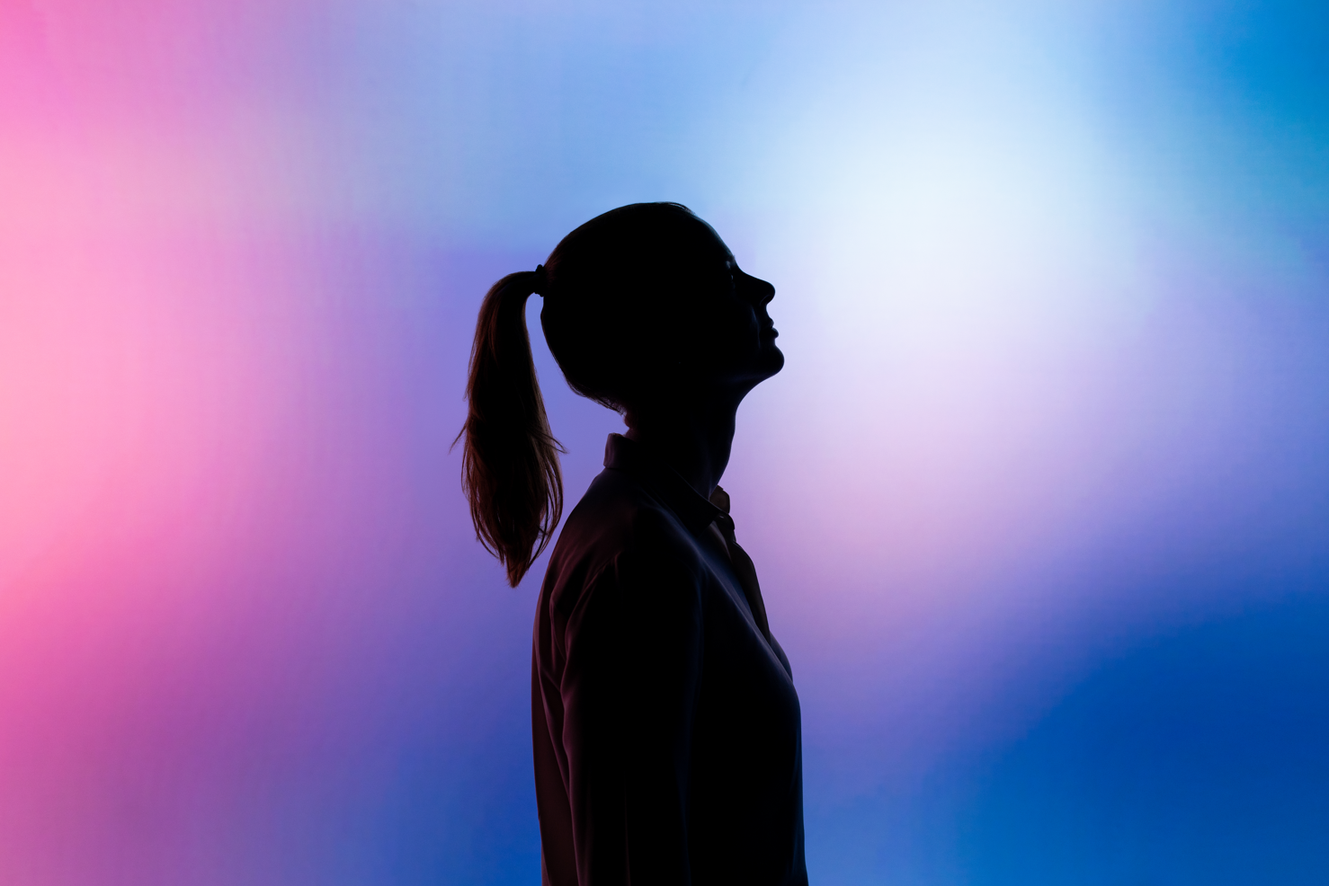 silhouette of woman in front of pink and blue background